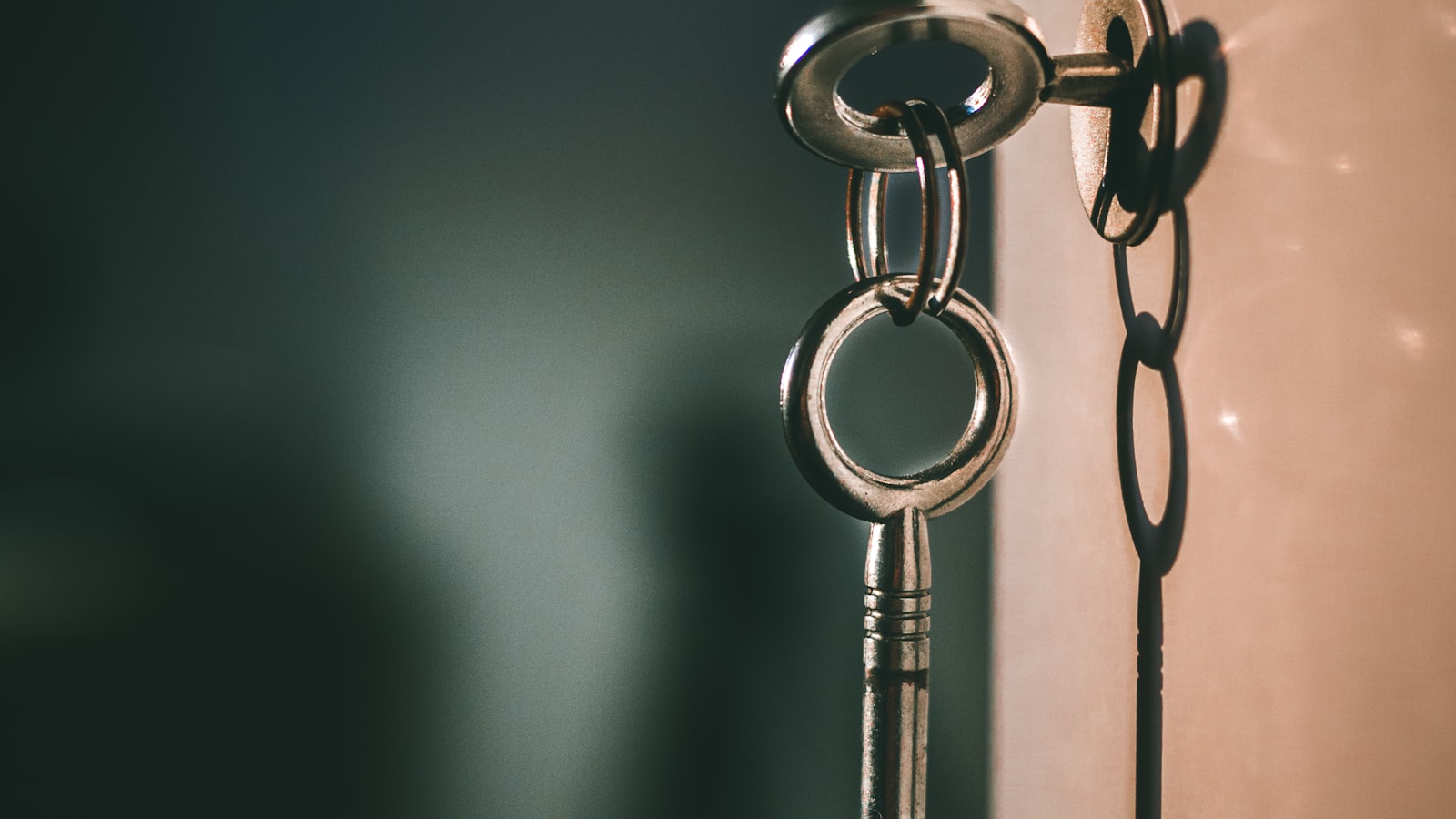 A single key hanging on a ring against a dark, warm-lit background