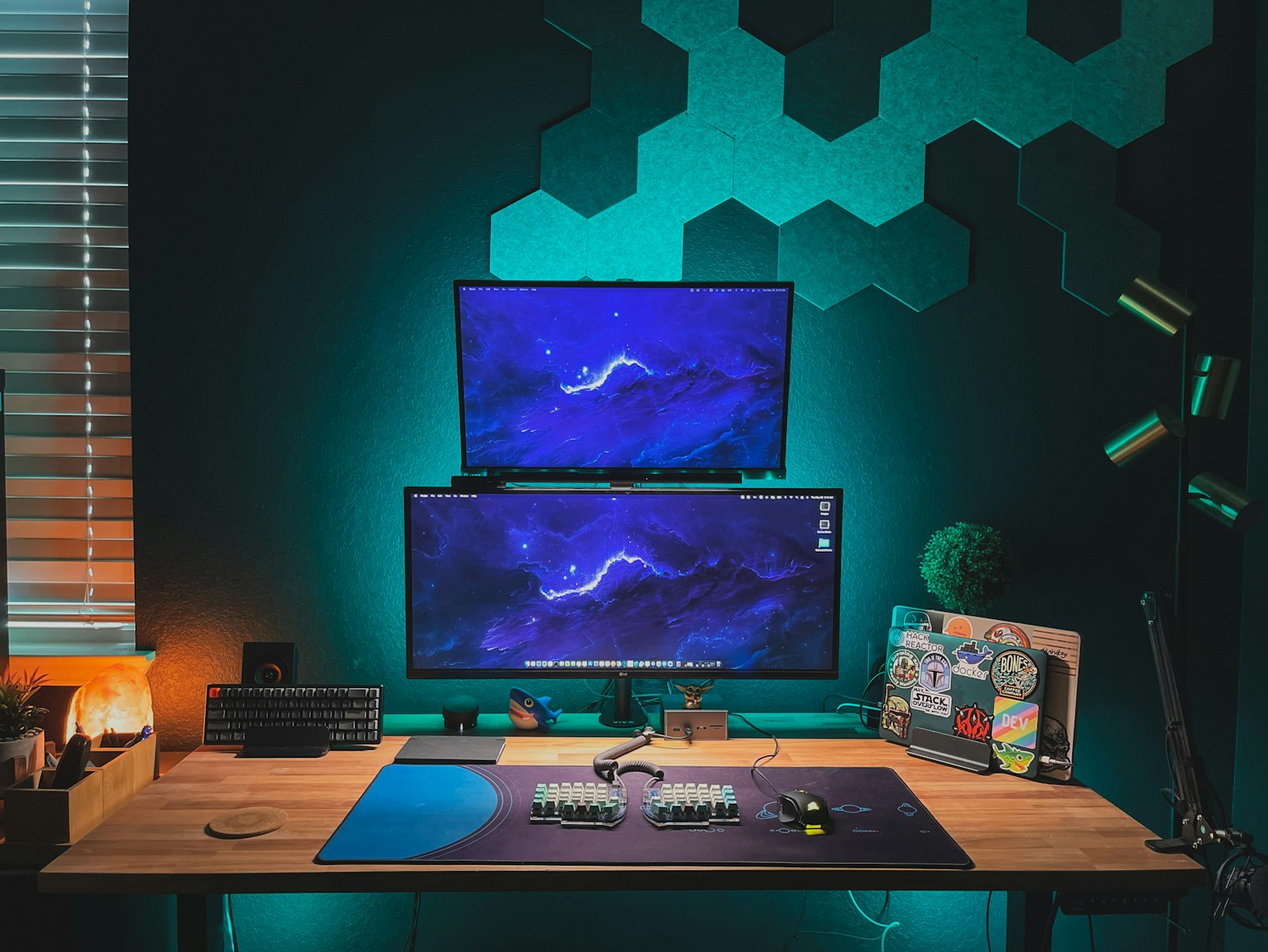 Home office desk with two stacked monitors, a laptop on a stand, and LED wall lighting