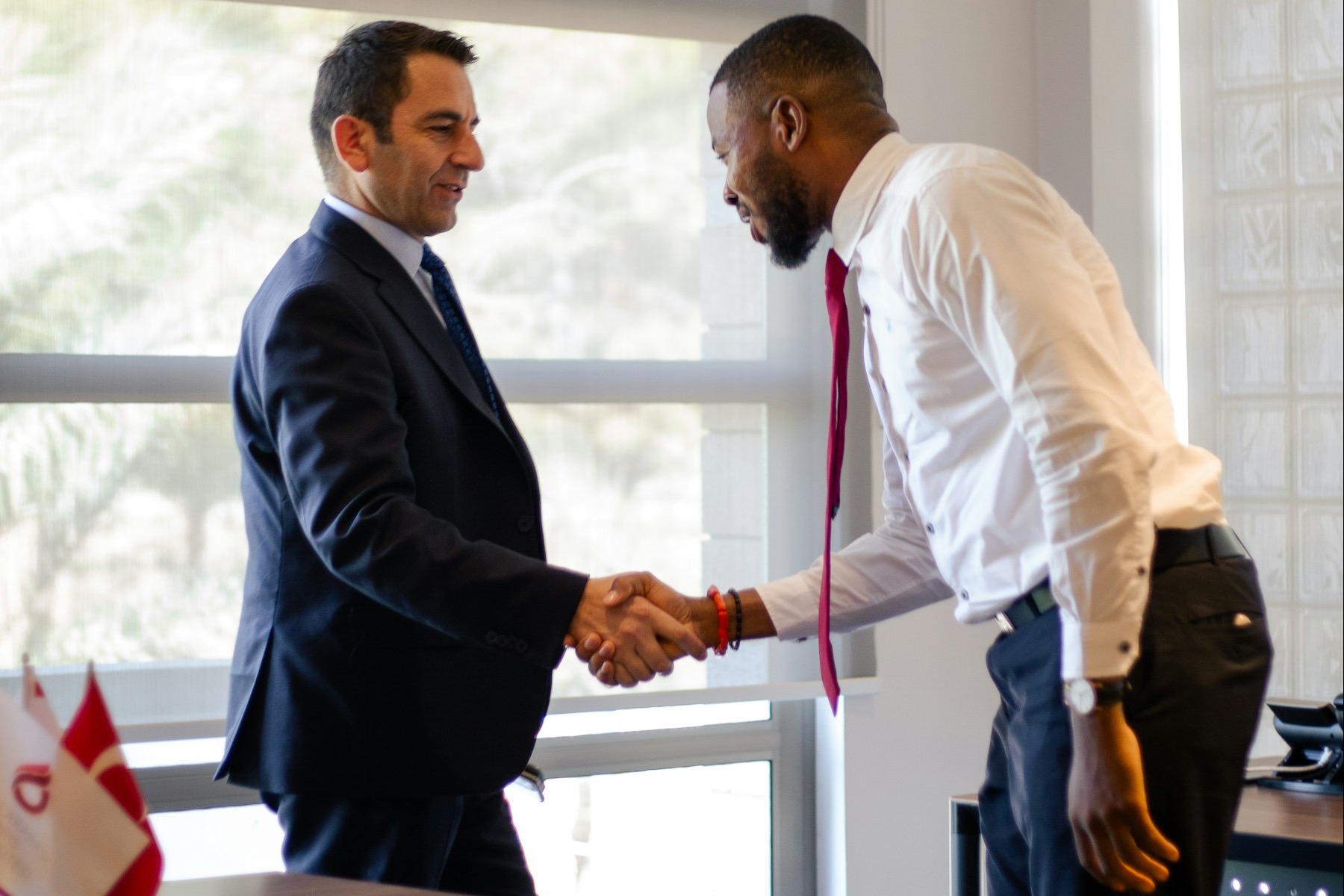 Two men shaking hands in front of an office window
