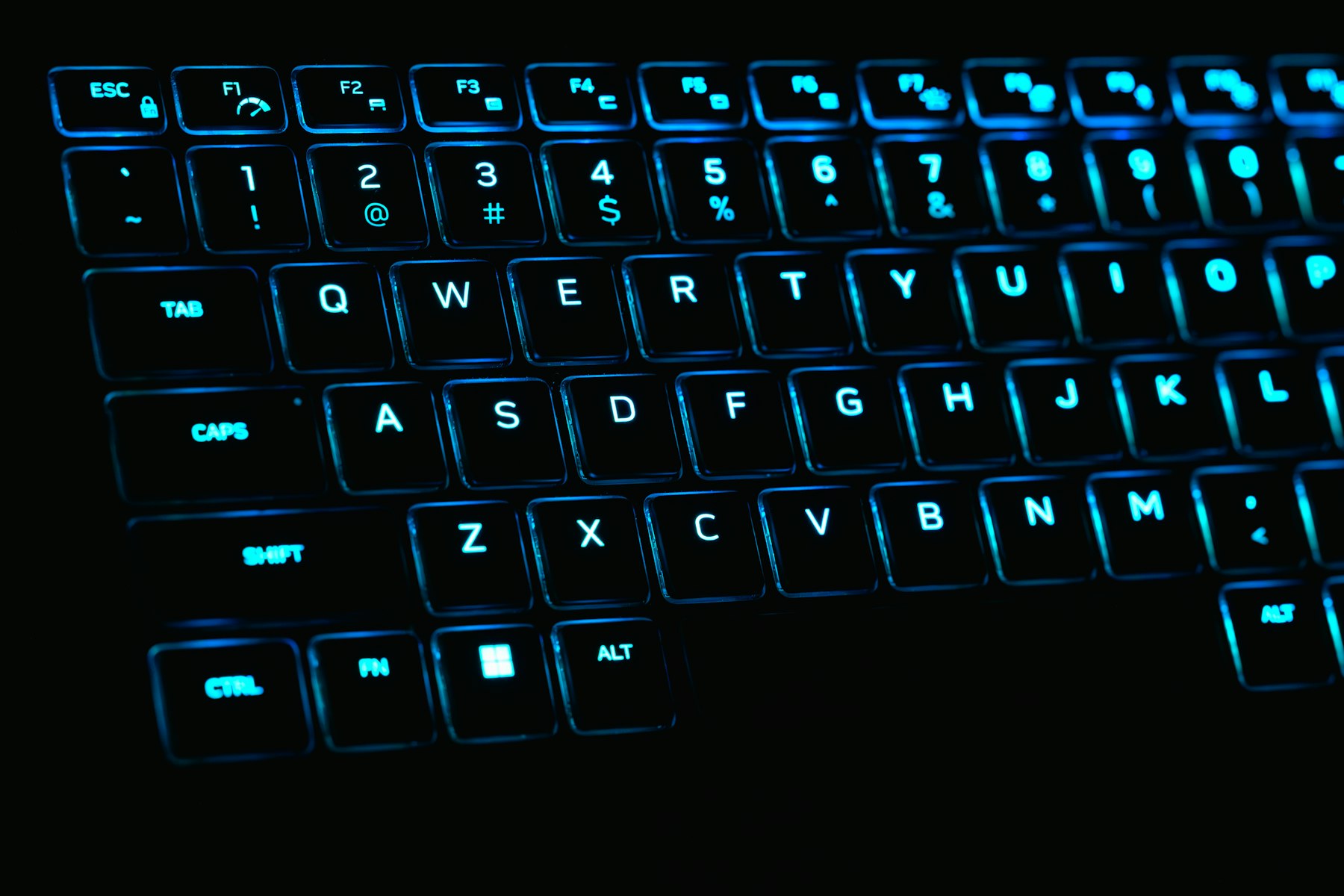 A keyboard with blue backlit keys in the dark