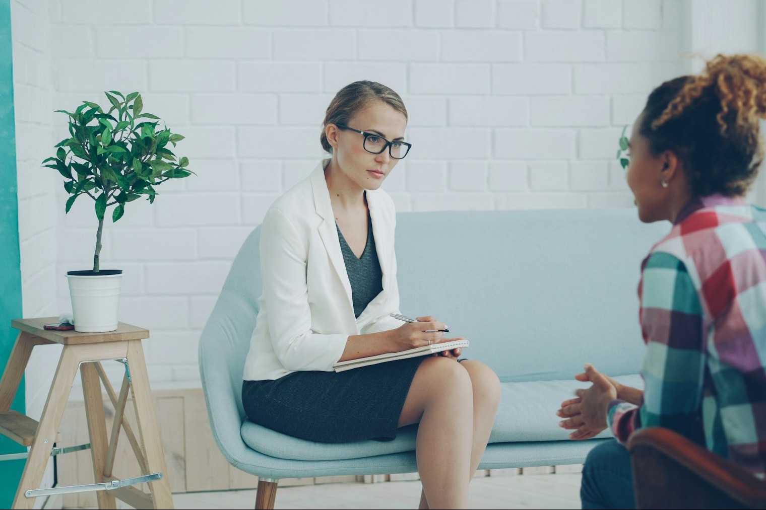 A counselor writing on a notepad while a client talks, seen from behind