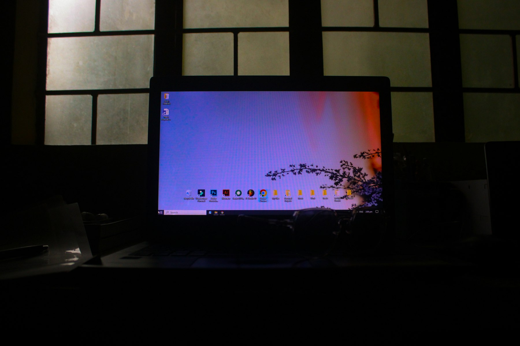 A laptop screen lit in a dark room in front of a paper screen